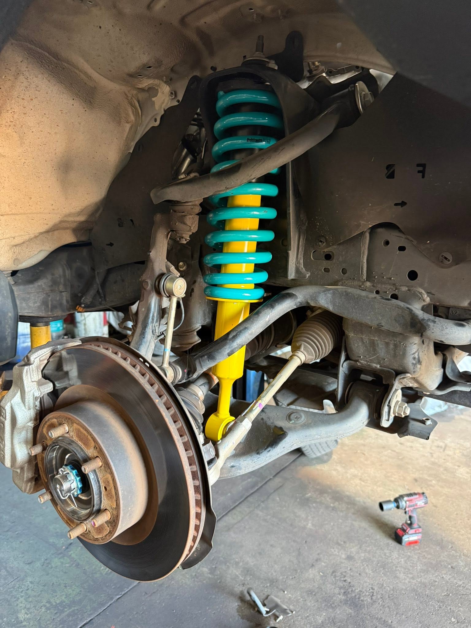 Rear leaf spring pack laid out beside a 4WD chassis